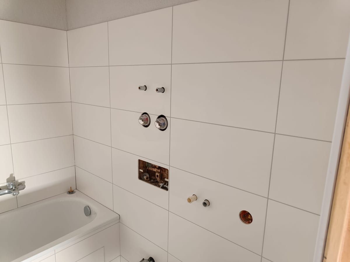 Wandanschlüsse über einer Badewanne im weiß gefliesten Bad